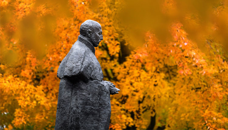 Statue of St. Ignatius surrounded by colorful fall leaves.