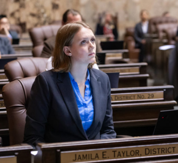 Maddie Sontag sitting in the senate chamber looking forward and listening. 