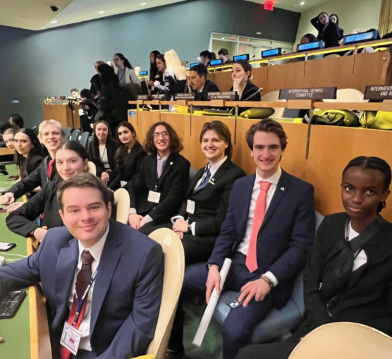 Gonzaga University Model United Nations delegates seated inside the United Nations Headquarters during the NMUN 2025 conference. The photo shows rows of desks with country nameplates, official conference badges, and participants preparing for committee sessions.