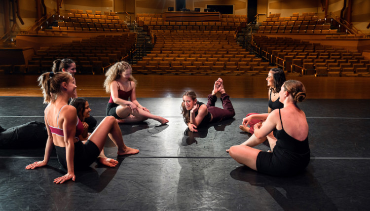 Dancers on stage seated together chatting