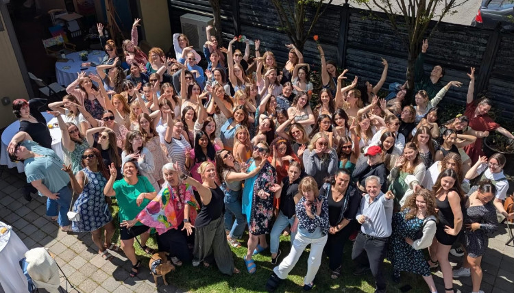 A dance alumni group photo taken in a courtyard. 