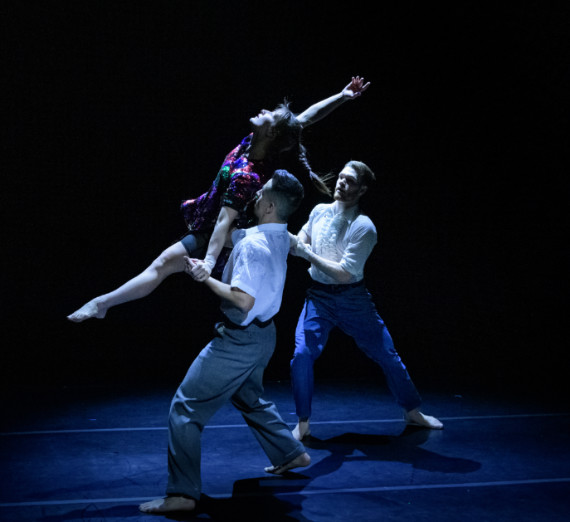 Two dancers holding a third in the air. 