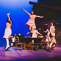 Three dancers performing on stage.