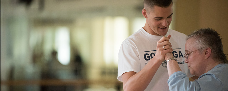 Gonzaga student smiles and dances with Parkinson’s dance participant.
