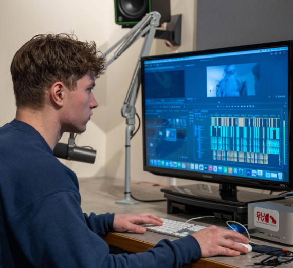 A student doing video editing at a computer. 