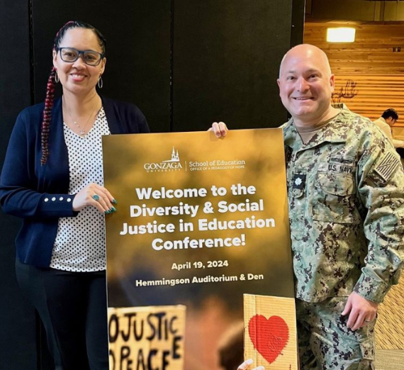 Two students standing with a welcome sign at the DSJ Conference