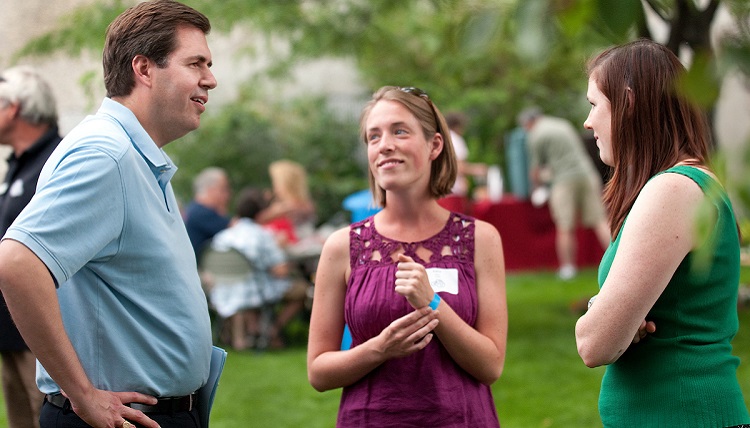 Three people having a conversation at a family picnic.