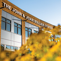 The Bollier Center building, viewed from an angle with yellow autumn leaves softly blurred in the foreground.