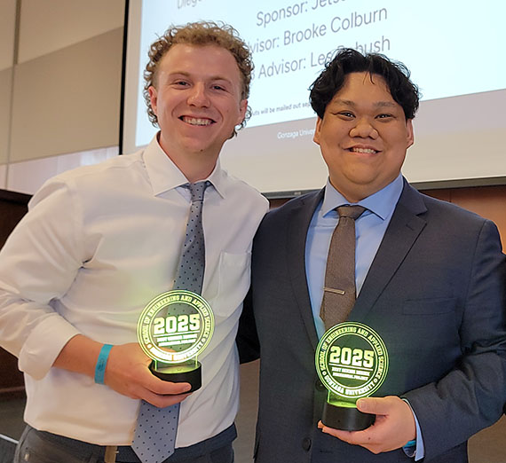 Two students showing presentation trophies