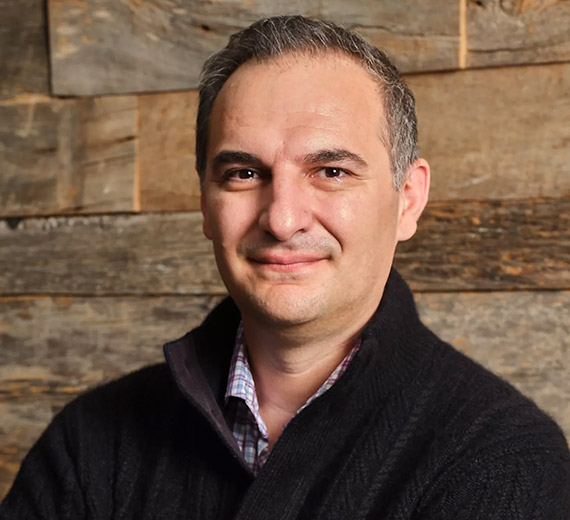doctor Andrew Trister looking at camera with brick wall behind him