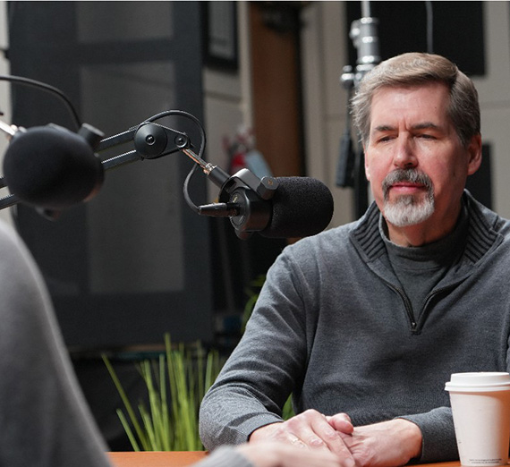 Thayne McCulloh behind a podcast microphone and a coffee cup in the foreground.
