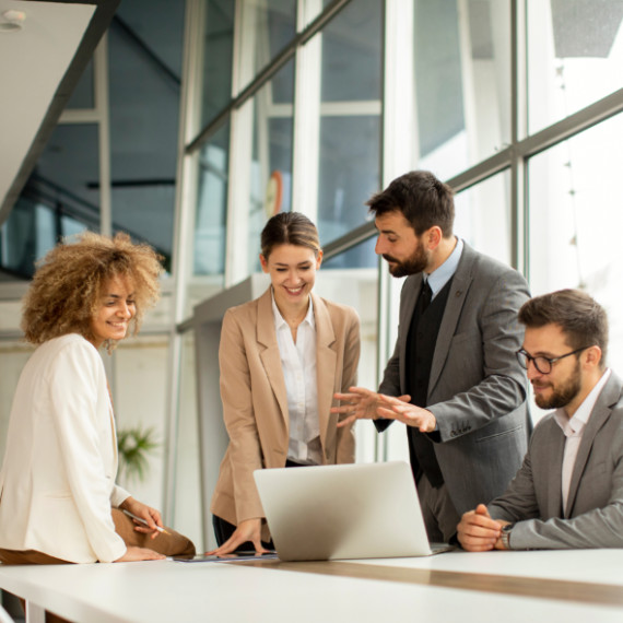 A group of businesspeople huddled over a laptop talking