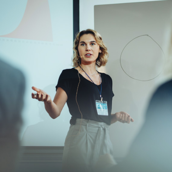 A woman standing in front of a whiteboard presenting to an audience