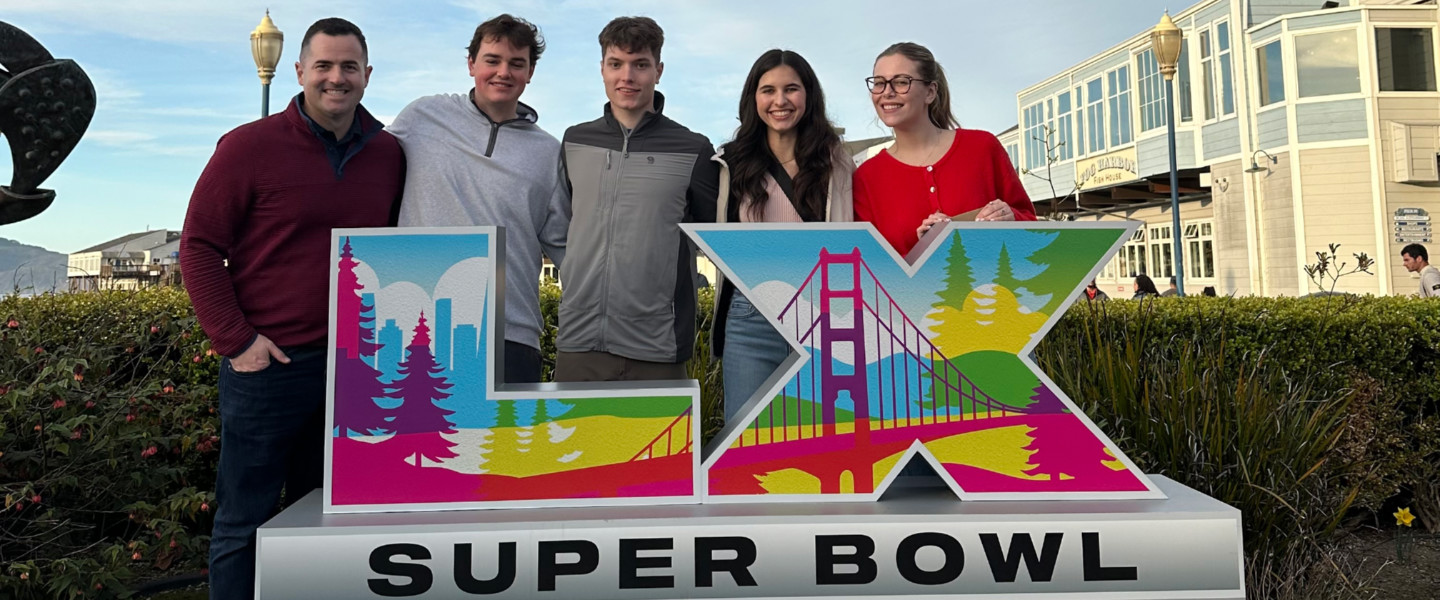 Gonzaga students Natalie Keller, Madylin Campbell, Kyle Sweeney and Michael Hanrahan with John Collett, M.A. of the Integrated Media Department standing behind a sign that Super Bowl LX. 