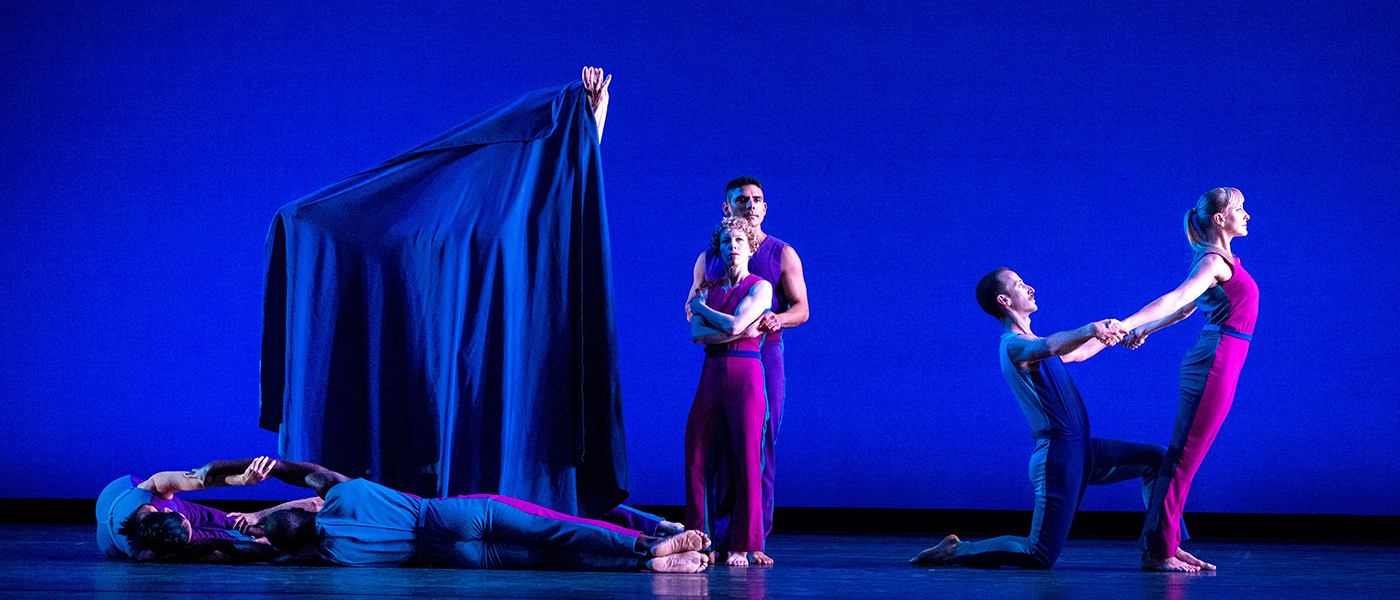 Dancers pose on stage with blue background.