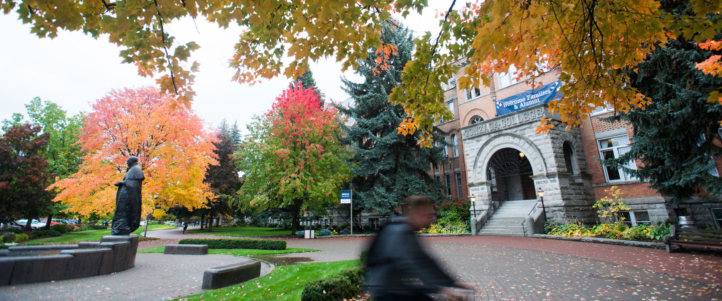 Student rides bike past college hall 