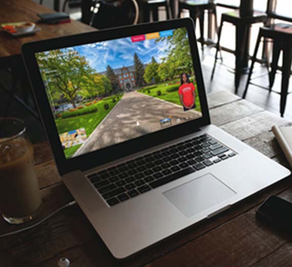 Three students sit on a lawn