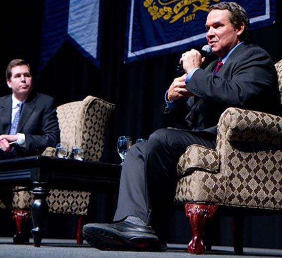 Greg Mortenson sits in a chair and interacts with an audience.