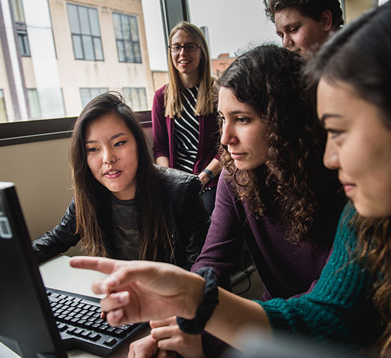 Five students gathered around a computer monitor.