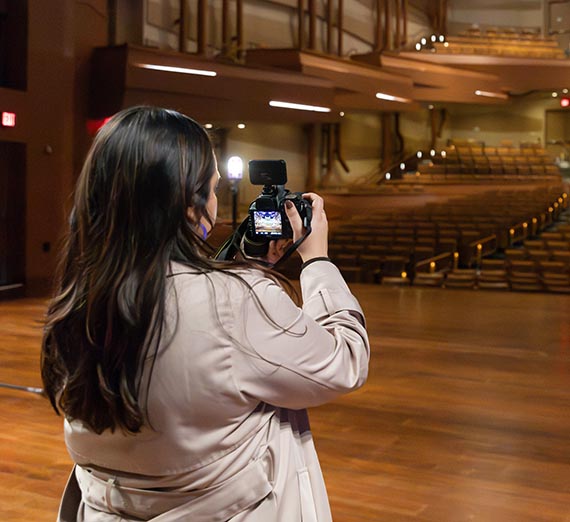 Women with camera standing on stage at the Martin Woldson Theater