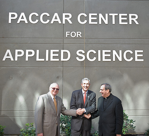 Three men shake hands in front of paccar