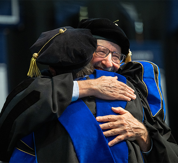 Dr.Chris Francovich hugging student at graduation 