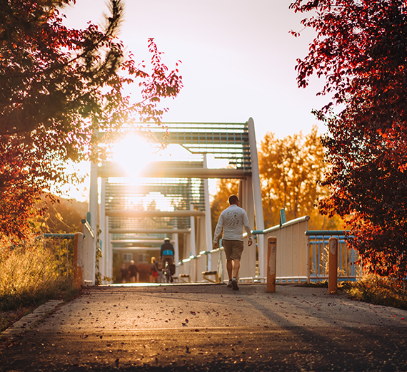 A student walks across a pedestrian bridge.