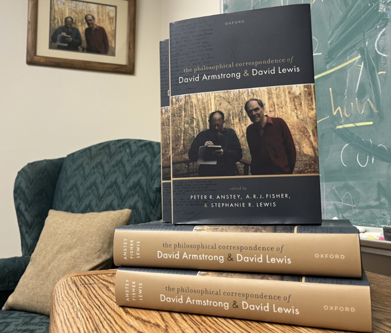 A stack of books titled The Philosophical Correspondence of David Armstrong & David Lews on a table in an office. 