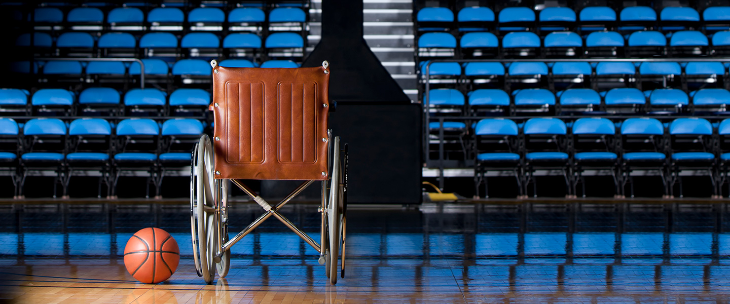 A wheelchair and a basketball sit on a basketball court