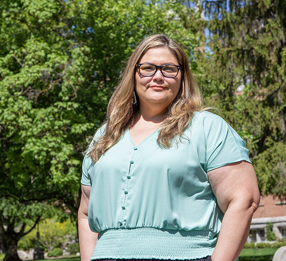 Helen Goodteacher, COML Alumna standing in front of trees 