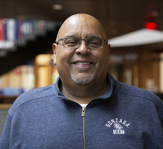 Juan Daniel Garcia wearing a Gonzaga zip up crewneck with interior building behind him. 