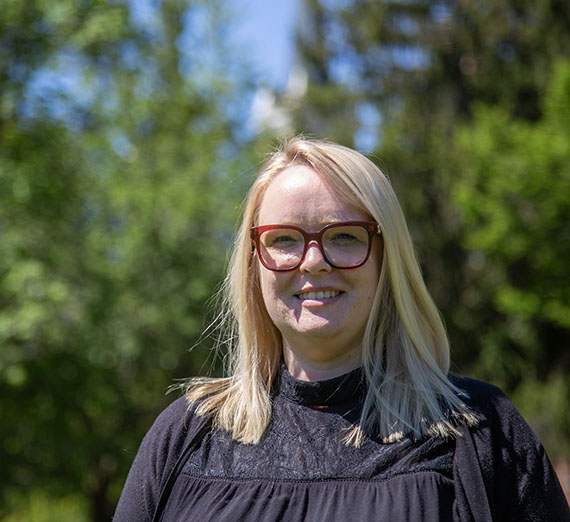 Woman in black top standing with campus greenery in the background 