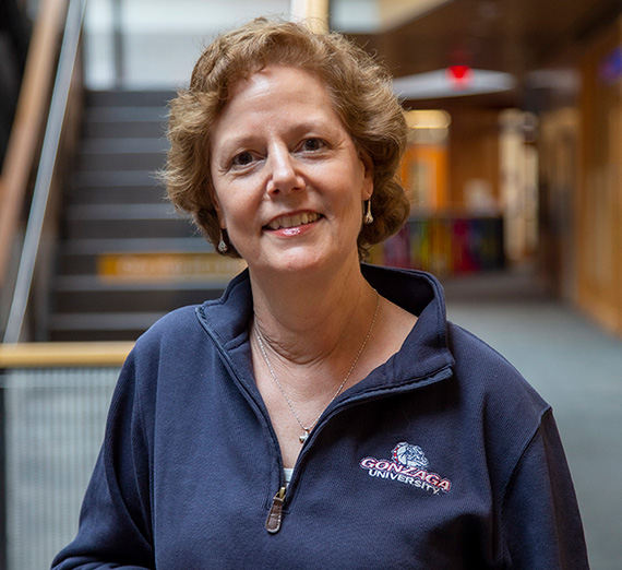 Woman in Gonzaga crewneck quarter zip sweatshirt with building interior in background. 