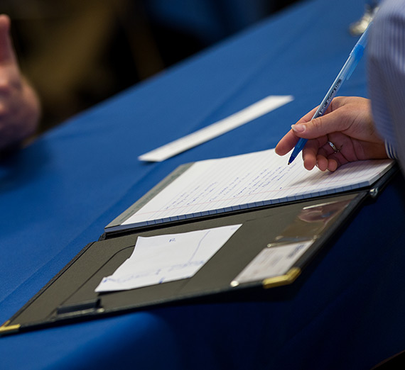 Person writing in a notebook during an interview