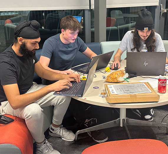 three male students work with computers