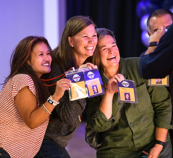 three attendees of Zagapalooza 2022 excitedly hold up their nametags