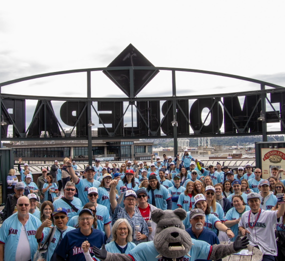 Attendees of the Zags Night at the Mariners event pose for a group photo wearing Mariners and Gonzaga University co-branded baseball jersey