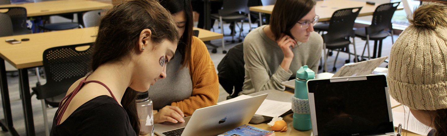 Four students gathered around a table studying together.