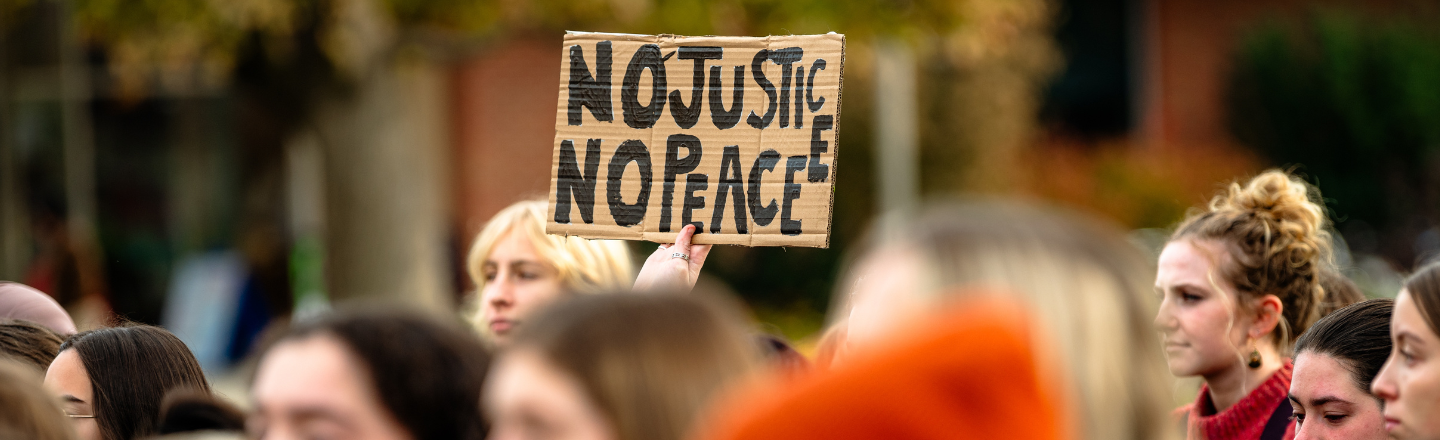 Student holding up a no justice no peace sign