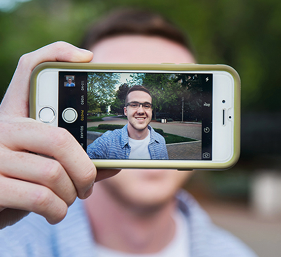 Konner Sauve holds up his phone, taking a portrait of himself. 