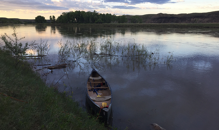 Canoes sit in river at dawn
