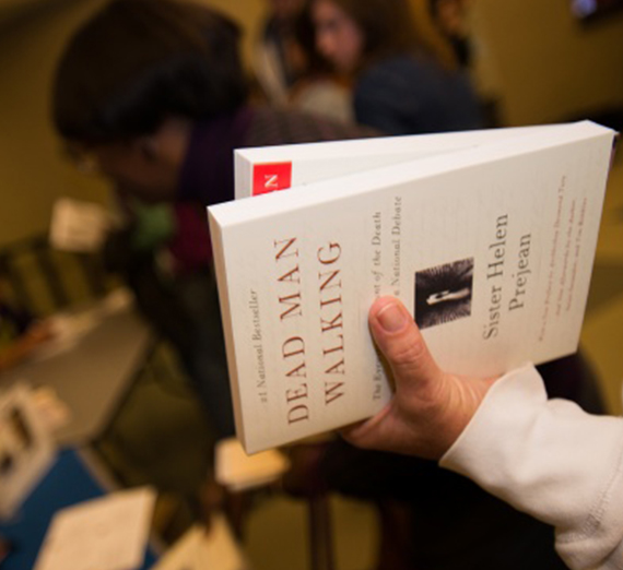 A hand holds a stack of books. 