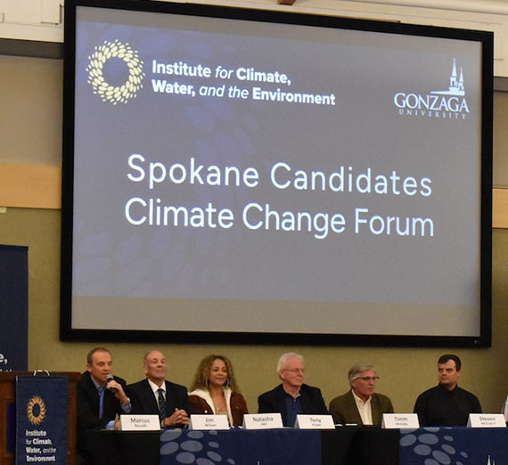 Panelists speak during a previous Spokane Candidates Climate Change Forum at Gonzaga University, seated below a large screen displaying the event title.