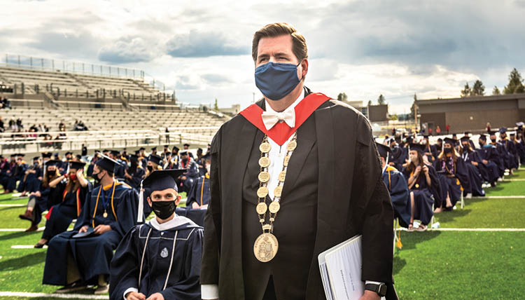 President McCulloh stands beside seated students at Gonzaga's commencement ceremony.
