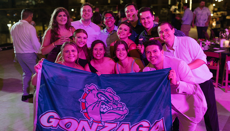 Taylor Gemmet and Anthony Rodman with fellow Zags at their wedding holding up a Gonzaga flag. 