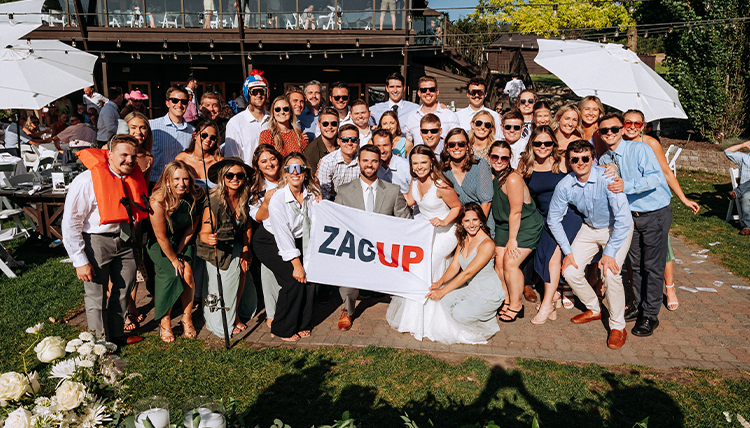 Sabrina Williams and Will Foley with wedding guests holding up a "Zag Up" flag.