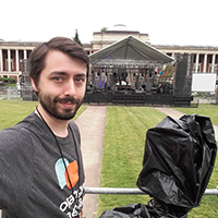 Steven poses with a camera at an outdoor event.