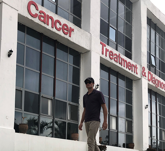 young alum walks in front of cancer center in Africa