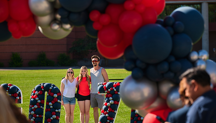 A man and his wife and daughter pose by a sign saying Go Zags