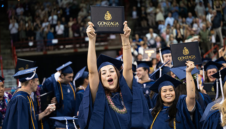 Two women hold up their degrees